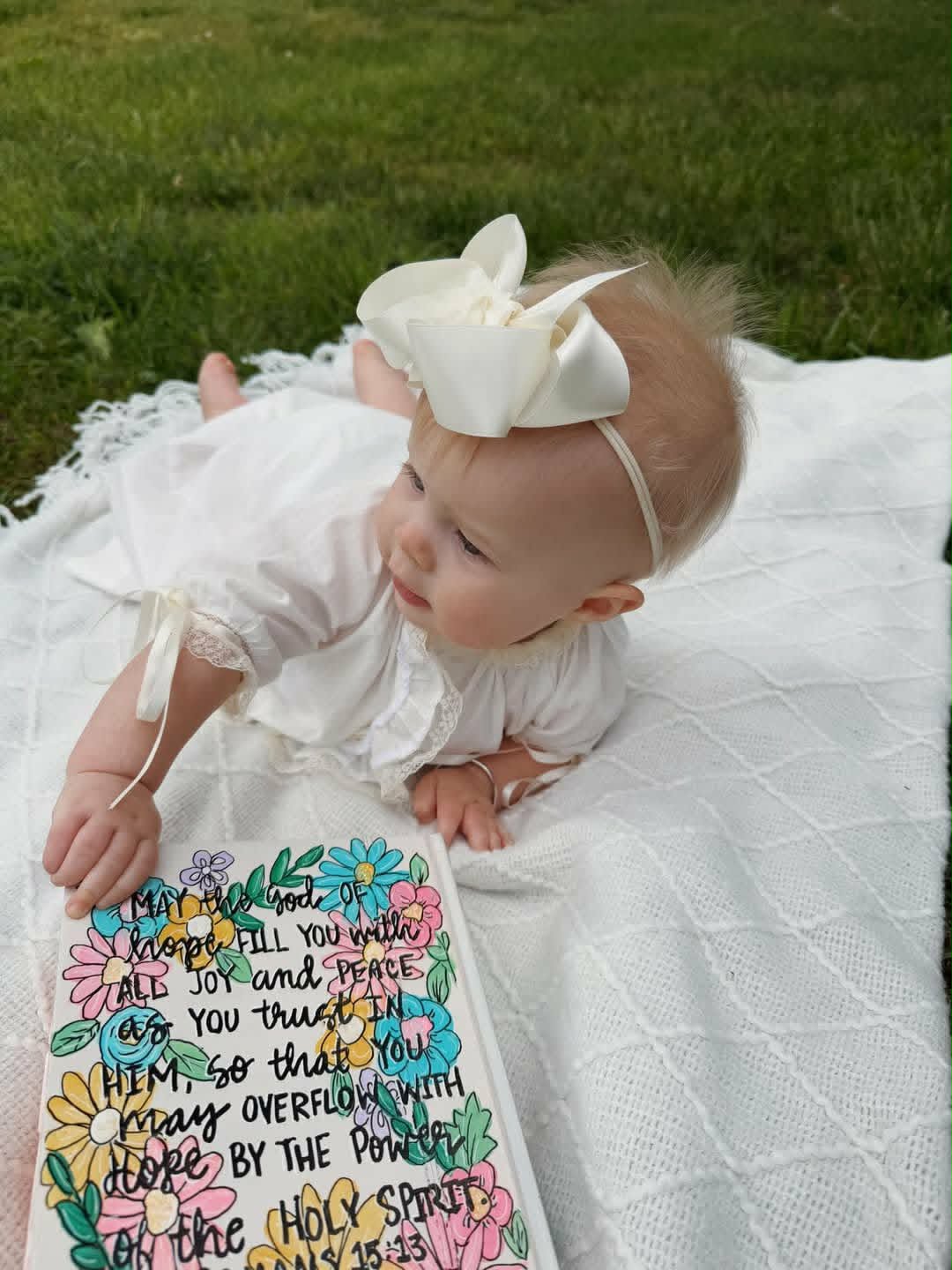 Baby on a hand-painted blanket with floral verse artwork