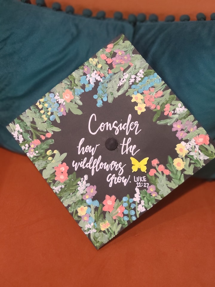 Graduation cap hand-painted with wildflowers and a Luke 12:27 verse