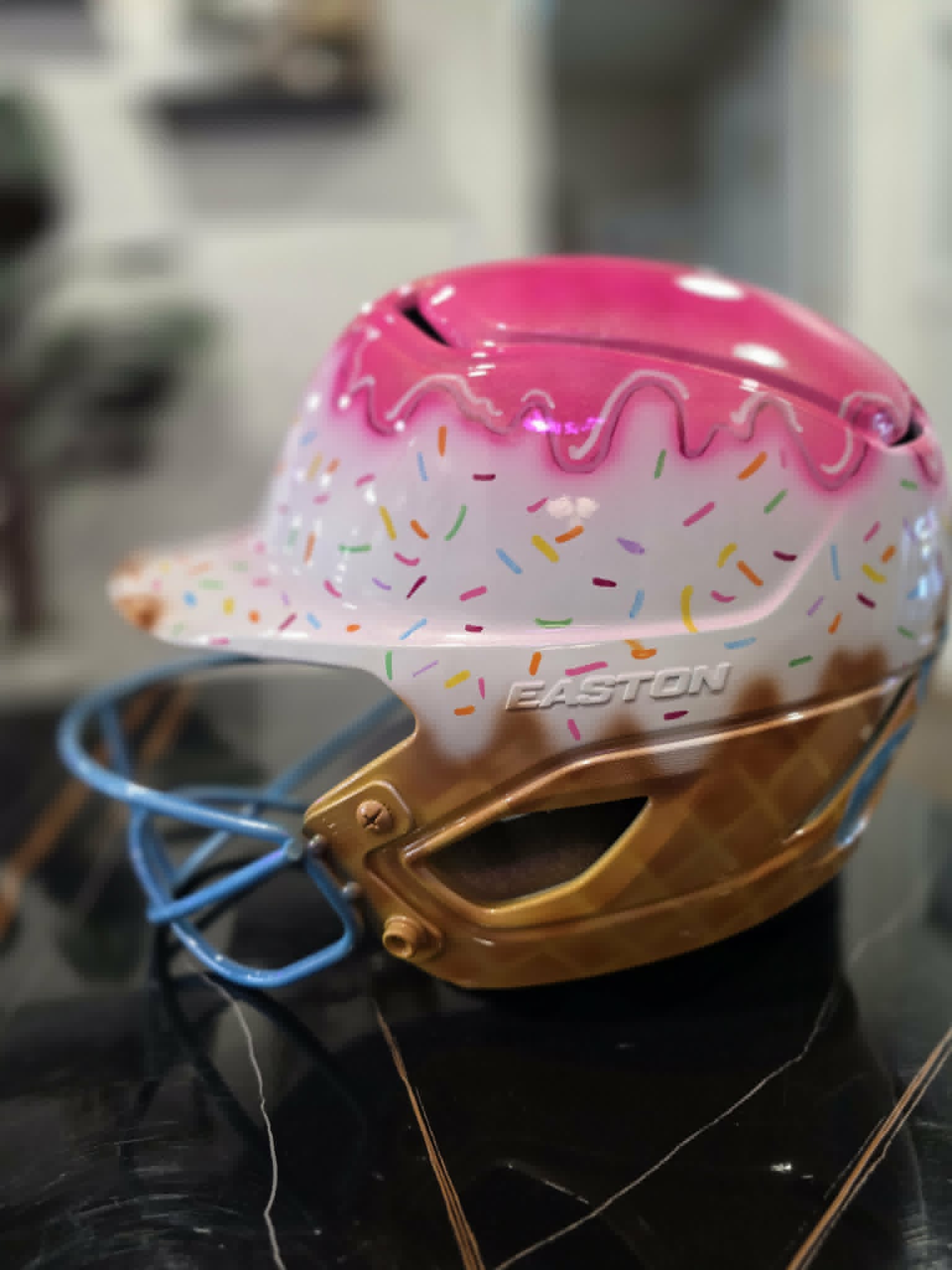 Softball batting helmet painted to look like a pink frosted birthday cake with sprinkles