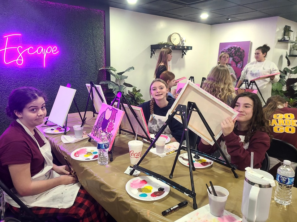 Group at a paint party in the studio with finished moonlit paintings
