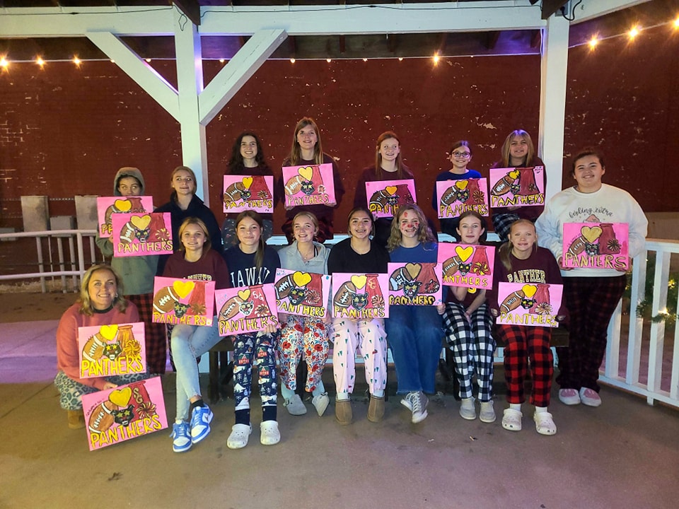 Group of kids posing with their finished paintings at a party